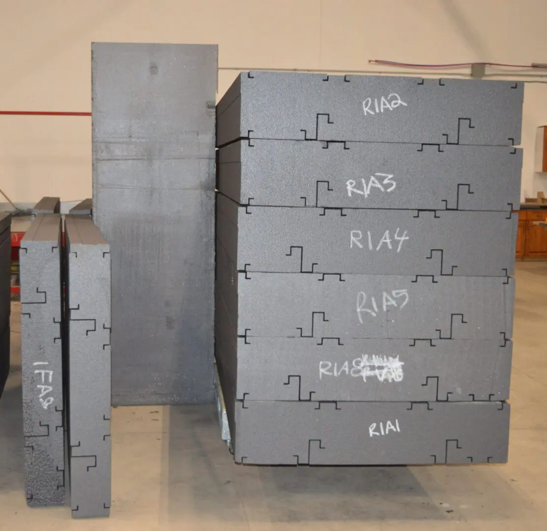 Stacked gray metal boxes labeled with various electrical terms in a workshop.