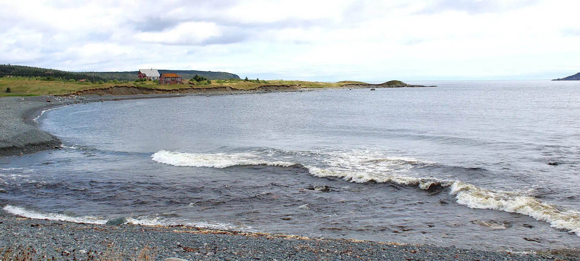 Calm coastal scene with gentle waves and rocky shore.