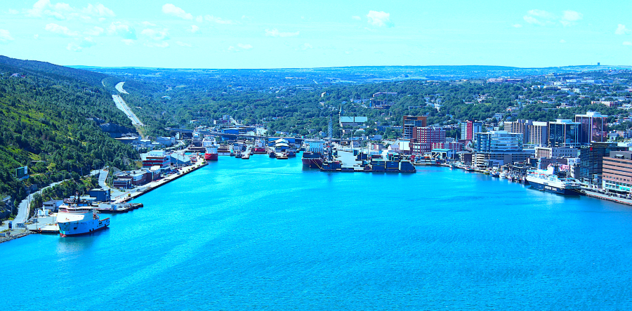 A vibrant harbor with boats docked along the coast and a town in the background.