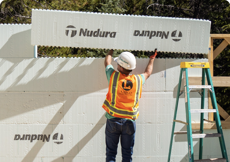 Worker installing insulation panels on a building exterior.