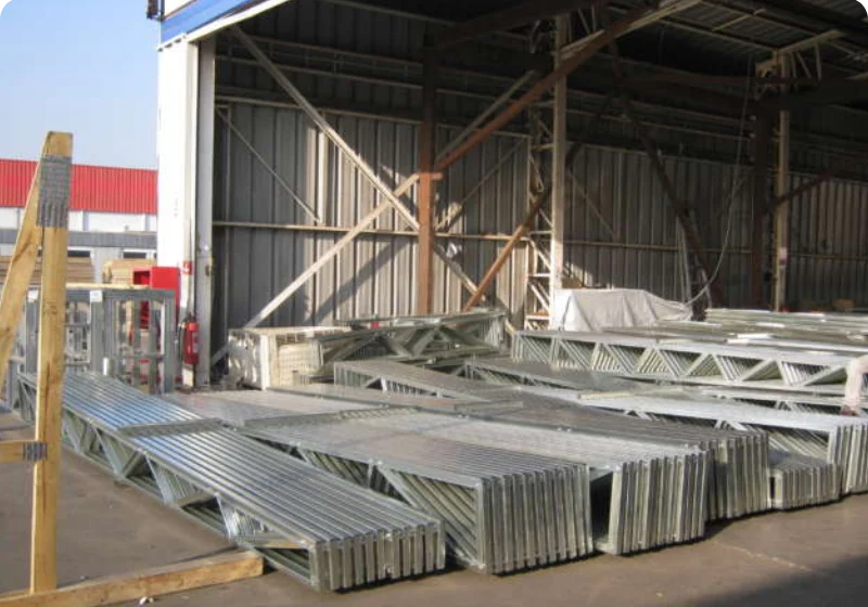 Stacked metal beams stored in an industrial warehouse.